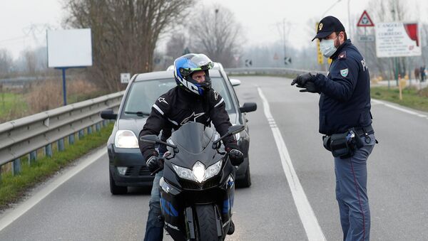 Полицейские в масках предупреждают водителей на дороге между Кодоньо и Казальпустерленго, которая была закрыта из-за вспышки коронавируса в северной Италии - Sputnik Грузия