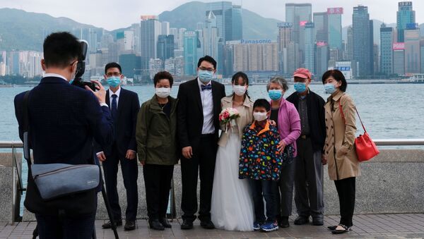 Молодожены в защитных масках фотографируются с семьей на память после регистрации брака в районе Цим Ша Цуй в Гонконге, Китай - Sputnik Грузия