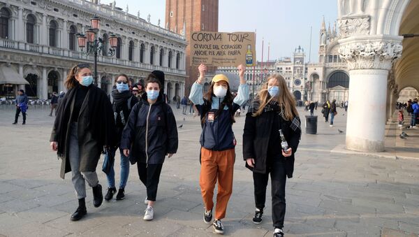 Группа девушек в защитных масках идет по площади Сан-Марко в Венеции с плакатом Корона-тур. Надо иметь смелость, даже чтобы бояться, после того, как последние дни Венецианского карнавала были отменены из-за вспышки коронавируса на севере Италии - Sputnik Грузия