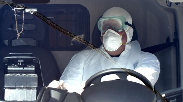 Водитель Скорой помощи 112 в маске и защитном костюме за рулем машины - Sputnik Грузия