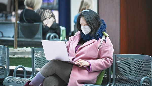 Женщина в медицинской защитной маске в аэропорту с ноутбуком во время мер по превенции коронавируса - Sputnik Грузия