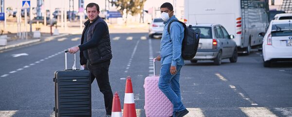 Пассажиры в масках в тбилисском аэропорту после прибытия идут на стоянку - Sputnik Грузия