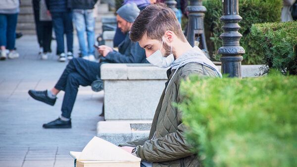 Молодой человек в маске на улице читает, защищаясь от коронавируса - Sputnik Грузия