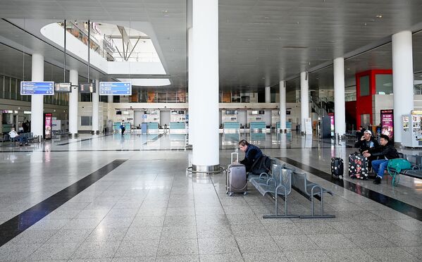 Опустевший зал ожидания и регистрации пассажиров в тбилисском аэропорту после прекращения полетов в страны риска  - Китай, Иран и Италию. Пассажиры, находящиеся в аэропорту, стараются не сидеть близко друг от друга - Sputnik Грузия