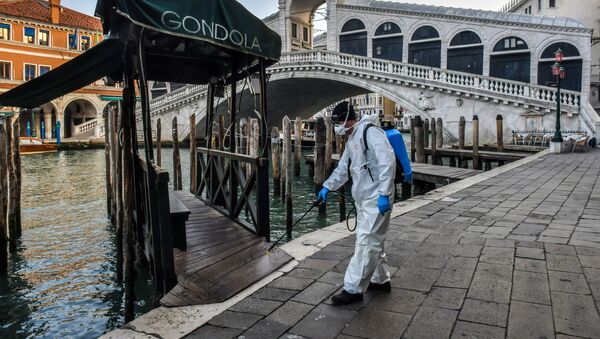 Сотрудник муниципальной компании Veritas распыляет дезинфицирующее средство в общественных местах на мосту Риальто в Венеции - Sputnik Грузия