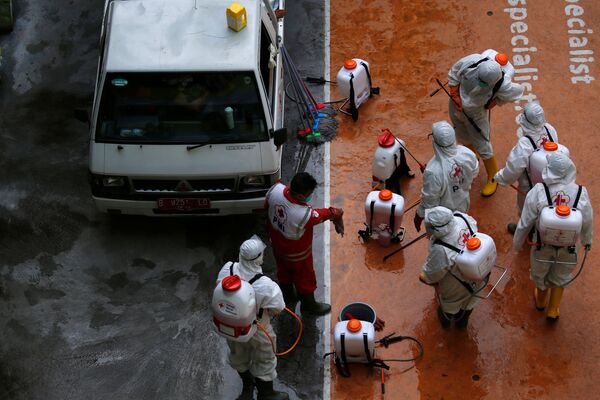 Волонтеры из Индонезийского Красного Креста готовятся к дезинфекции школы в Джакарте, которая как и другие учебные заведения, была закрыта в связи со вспышкой опасного коронавируса - Sputnik Грузия
