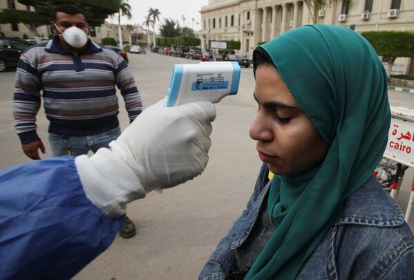 Медицинский работник проверяет температуру у молодой женщины на улице неподалеку от Каирского университета. В Каире обучение в вузах пока приостановлено частично. В Египте зафиксировано около 170 подтвержденных случаев коронавируса - Sputnik Грузия