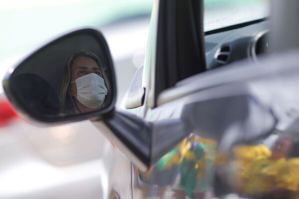 Женщина в защитной маске за рулем автомобиля в городе Бразилиа. В Бразилии сегодня зафиксировано более 230 подтвержденных случаев коронавируса, скончались два человека - Sputnik Грузия