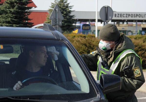 Украинский пограничник меряет температуру у водителя на КПП на границе с Польшей. Тем временем в Евросоюзе готовятся на 30 дней запретить въезд на территорию ЕС всем иностранцам - Sputnik Грузия