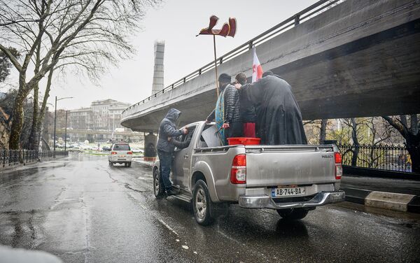 Некоторые автомобилисты прямо из окон своих машин снимали на фото и видео внедорожники со священниками, которые освящали улицы - Sputnik Грузия
