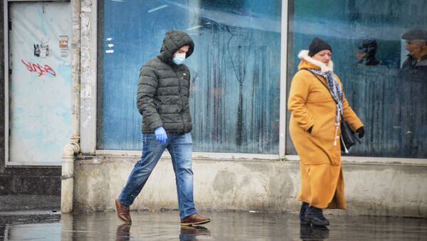 Молодой мужчина в защитной маске идет по улице. В Грузии принимаются меры по борьбе с коронавирусом - Sputnik Грузия