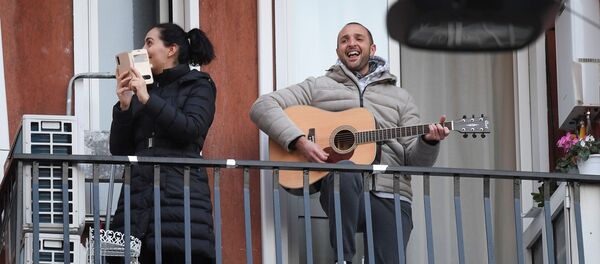 Мужчина с гитарой и женщина со смартфоном на одном из балконов в Милане - Sputnik Грузия