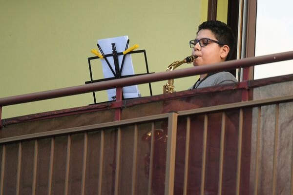Звуки музыки лились отовсюду: мальчик играет на саксофоне на балконе своего дома во время карантина в Милане - Sputnik Грузия