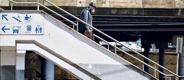 Пожилой мужчина в защитной маске идет по переходному мосту у железнодорожного вокзала - Sputnik Грузия