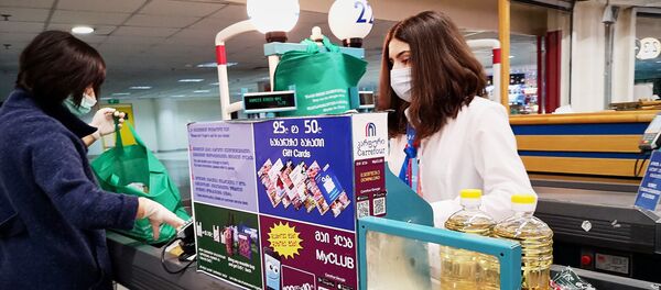 Продавщица и покупатель в масках и перчатках в супермаркете. Власти страны борются с коронавирусом. В стране введено чрезвычайное положение - Sputnik Грузия