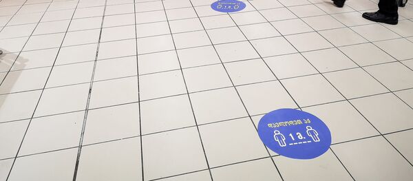 Наклейки на полу в супермаркете, призывающие покупателей выдерживать дистанцию друг от друга в полтора метра. В Грузии борются с коронавирусом - Sputnik Грузия
