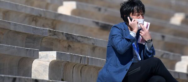 Мужчина в медицинской маске на стадионе во время церемонии передачи Японии огня летних Олимпийских игр, Афины Мужчина в медицинской маске на стадионе во время церемонии передачи Японии огня летних Олимпийских игр, Афины - Sputnik Грузия