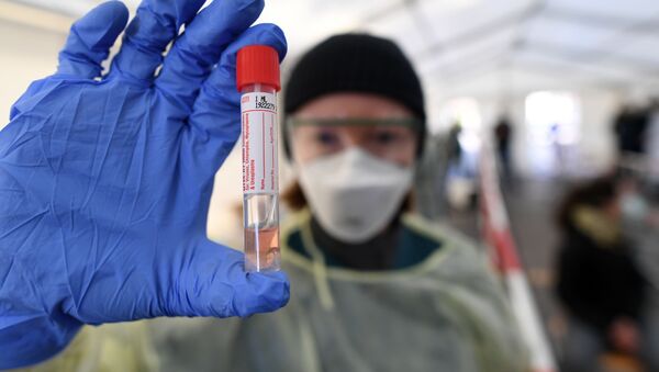 Медик держит в руках тест на коронавирус COVID-19 в центре проверки для работников опасных профессий. Мюнхен, Германия - Sputnik Грузия