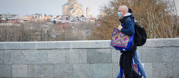 Люди идут в масках по Сухому мосту на фоне собора Святой Троицы Самеба. В Грузии борются с коронавирусом Люди идут в масках по Сухому мосту на фоне собора Святой Троицы Самеба. В Грузии борются с коронавирусом - Sputnik Грузия