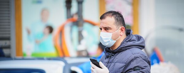 Мужчина с телефоном в маске и перчатках идет по улице. В Грузии борются с коронавирусом - Sputnik Грузия