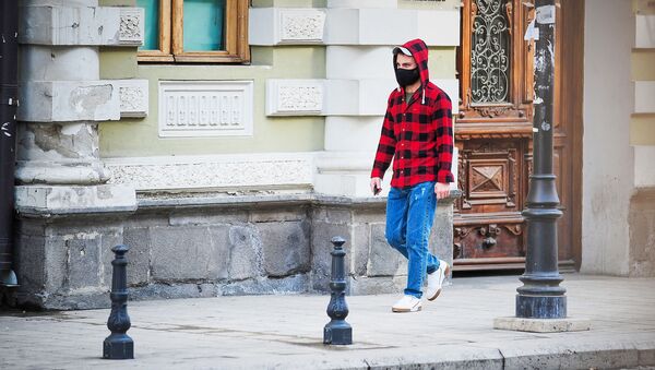 Молодой человек идет по улице в черной маске. В Грузии борются с коронавирусом - Sputnik Грузия