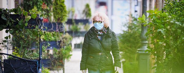 Пожилая женщина идет по улице в медицинской маске. В Грузии борются с коронавирусом - Sputnik Грузия