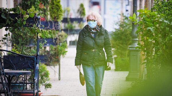 Пожилая женщина идет по улице в медицинской маске. В Грузии борются с коронавирусом - Sputnik Грузия