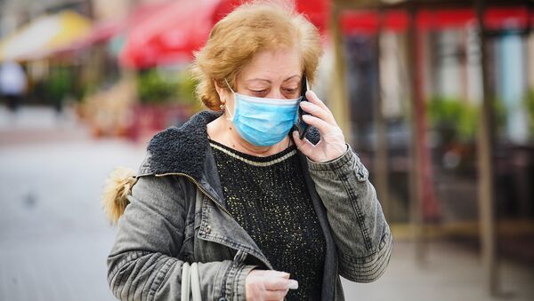 Пожилая женщина идет по улице в маске и перчатках, и говорит по телефону. В Грузии борются с коронавирусом - Sputnik Грузия
