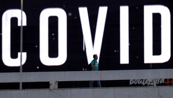 Человек идет мимо громадного экрана с надписью COVID-19 предупреждающего об опасности коронавируса в Бразилии - Sputnik Грузия
