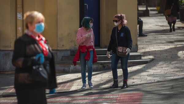 Девушки в медицинских масках и в перчатках идут по улице в Тбилиси. В Грузии борются с коронавирусом - Sputnik Грузия