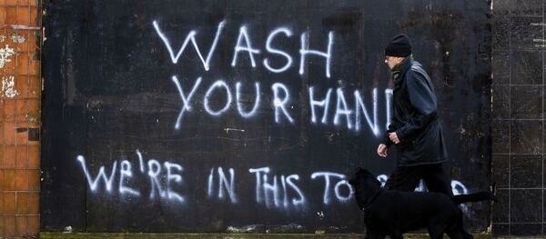 Мужчина с собакой напротив граффити с призывом мыть руки в Северной Ирландии  - Sputnik Грузия