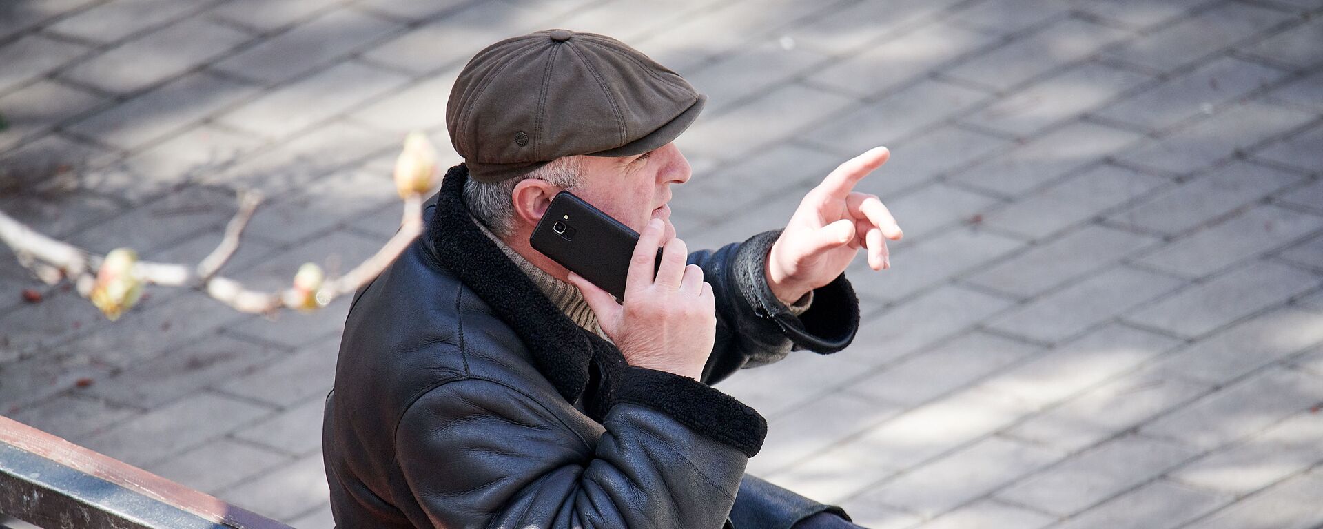 Мужчина сидит на скамейке в парке с покупками из магазина и говорит по телефону. В Грузии введен карантин и принимаются меры по борьбе с коронавирусом - Sputnik Грузия, 1920, 25.04.2021