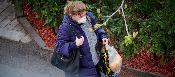 Женщина в респираторе с продуктами из магазина идет по улице. В Грузии введен комендантский час и карантин - Sputnik Грузия