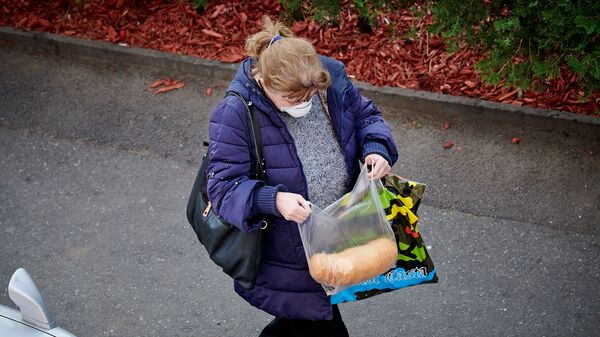 Женщина в респираторе с продуктами из магазина идет по улице. В Грузии введен комендантский час и карантин - Sputnik Грузия