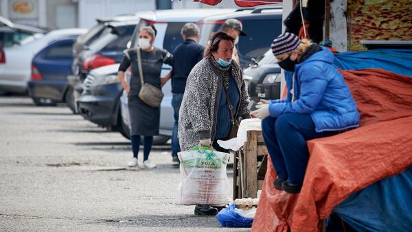 Пожилая женщина в маске и с сумками идет по территории рынка - Sputnik Грузия