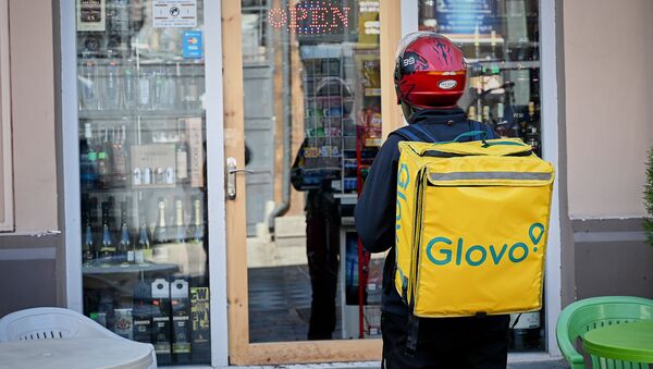 Курьер Glovo отражается в витрине продуктового магазина, где выставлена алкогольная продукция - Sputnik Грузия