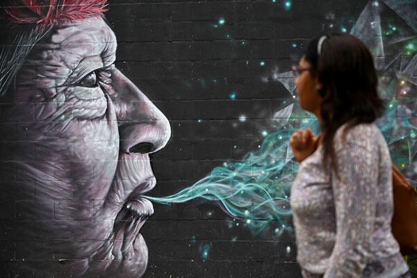 Женщина проходит мимо граффити, нарисованного в рамках фестиваля Graficalia в городе Кали в Колумбии - Sputnik Грузия