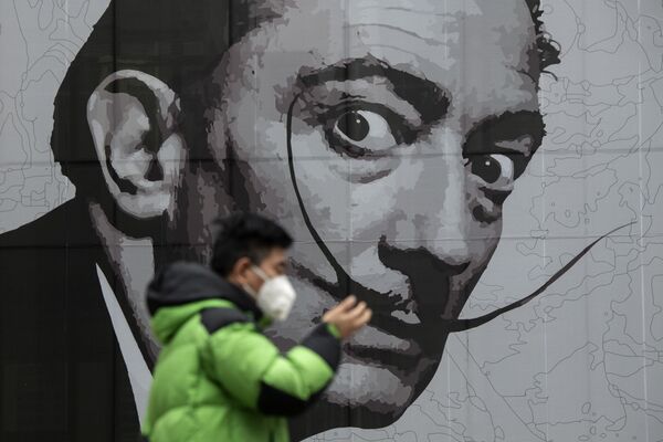 Во вторник Китай заявил, что впервые с начала пандемии в стране не было зафиксировано ни одной смерти, связанной с коронавирусом. Однако местные жители не спешат снимать маски. На фото мужчина на фоне граффити с изображением Сальвадора Дали в Шанхае - Sputnik Грузия