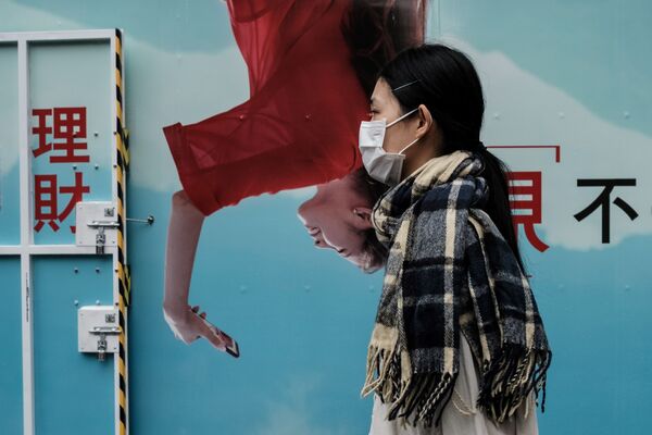 В адрес Китая, ставшего очагом распространения коронавируса, прозвучало немало лестных слов о мерах, которые страна ввела для борьбы с инфекцией. На фото девушка напротив рекламного плаката в Гонконге  - Sputnik Грузия