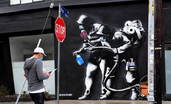 Прохожий напротив граффити, посвященного борьбе с коронавирусом, в Лос-Анджелесе - Sputnik Грузия