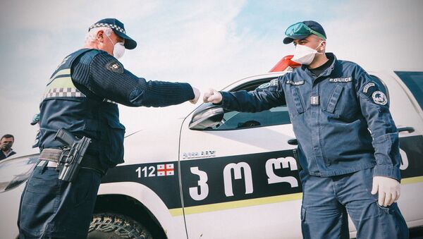 Сотрудники региональной полиции в масках и перчатках приветствуют друг друга во время карантина - Sputnik Грузия