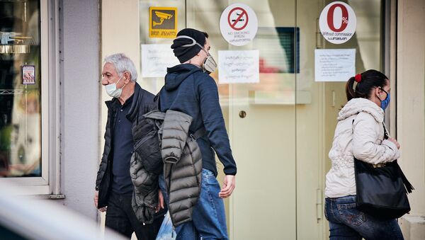 Молодой человек в респираторе и люди в масках идут по улице в столице Грузии - Sputnik Грузия