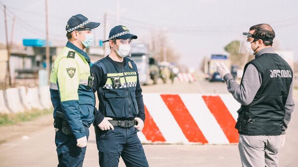 Сотрудники полиции в масках на блокпосту во время карантина - Sputnik Грузия
