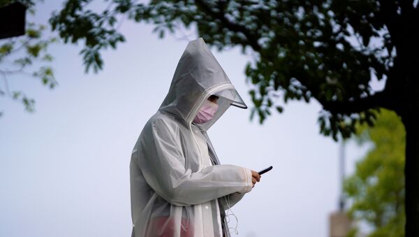 Прохожий в маске смотрит в мобильное устройство. Ситуация в Китае в связи с коронавирусом - Sputnik Грузия