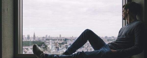 Самоизоляция. Молодой человек сидит на подоконнике и смотрит в окно - Sputnik საქართველო
