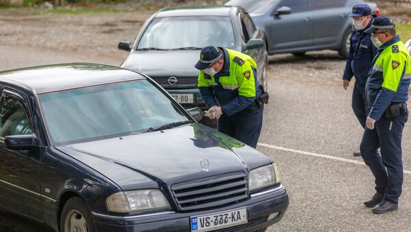 Полицейские на блокпосту во время эпидемии коронавируса проверяют автомашины - Sputnik Грузия