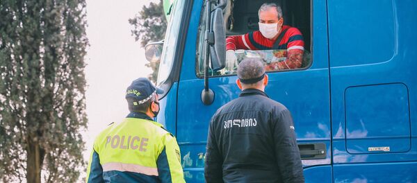 Полицейские на блокпосту в регионе во время эпидемии коронавируса проверяют автомашины - Sputnik Грузия