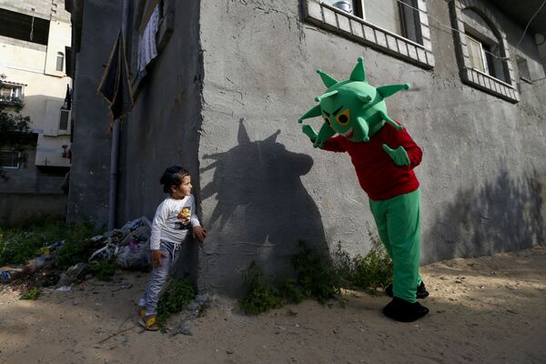 Палестинец в костюме коронавируса играет с девочкой в ​​центральной части Сектора Газа во время пандемии COVID-19 - Sputnik Грузия