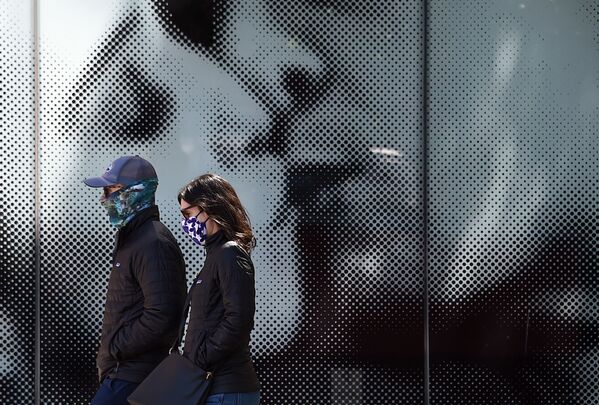 Пара в защитных масках проходит мимо афиши у кинотеатра в Вашингтоне - Sputnik Грузия