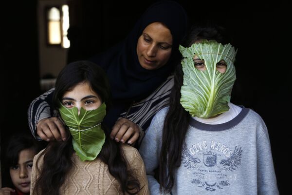 На фоне пандемии коронавируса в Палестине, мать надевает своим детям маски из листьев капусты - Sputnik Грузия